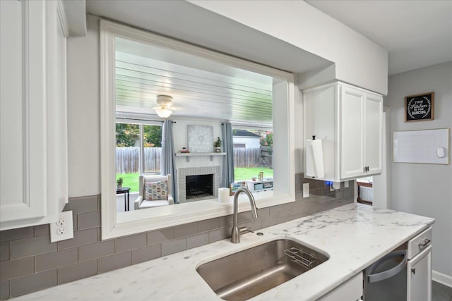 kitchen featuring light stone counters, sink, and white cabinetry