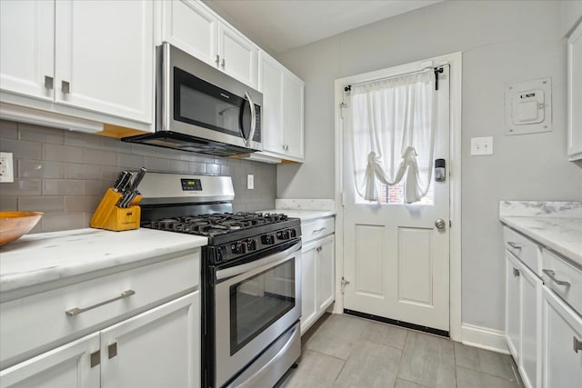 kitchen featuring white cabinetry, light stone countertops, decorative backsplash, and stainless steel appliances