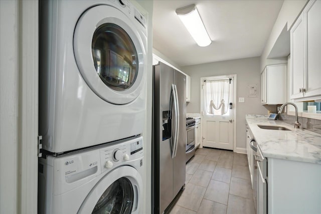 clothes washing area with stacked washer / dryer, sink, and light tile patterned floors