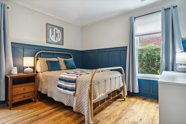 bedroom featuring ornamental molding and light hardwood / wood-style flooring