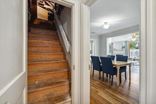 stairway with crown molding and wood-type flooring