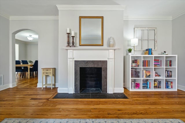 interior space featuring crown molding, a tiled fireplace, and hardwood / wood-style floors