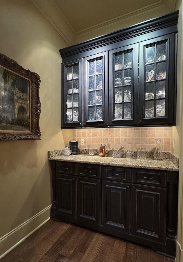 bar with backsplash, crown molding, light stone countertops, and dark hardwood / wood-style floors