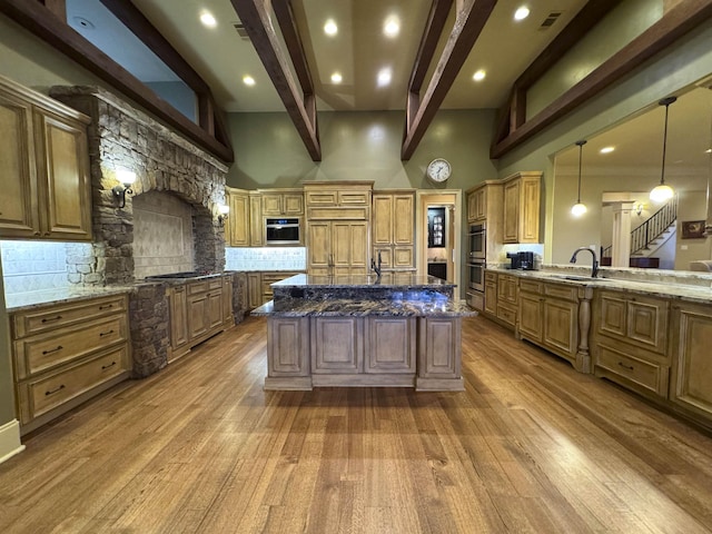 kitchen with pendant lighting, dark stone counters, a large island, and backsplash