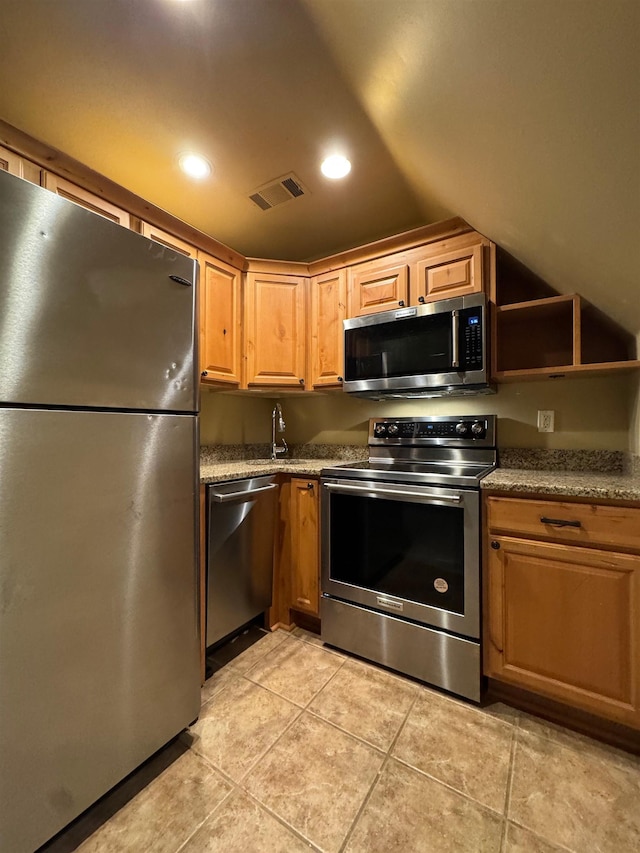 kitchen with light tile patterned flooring, stainless steel appliances, sink, and vaulted ceiling