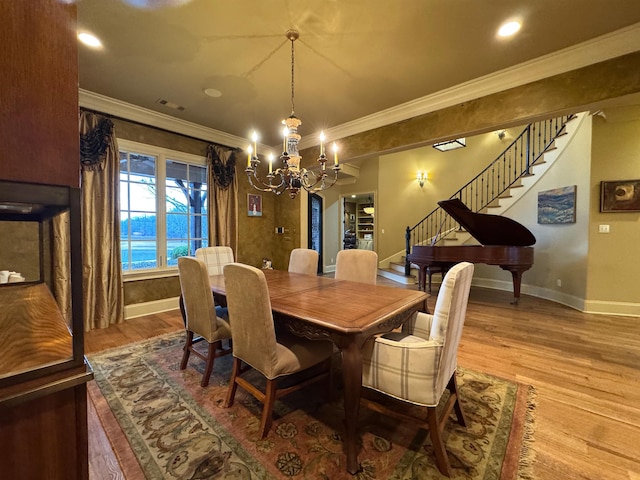 dining space with ornamental molding, a notable chandelier, and light hardwood / wood-style floors