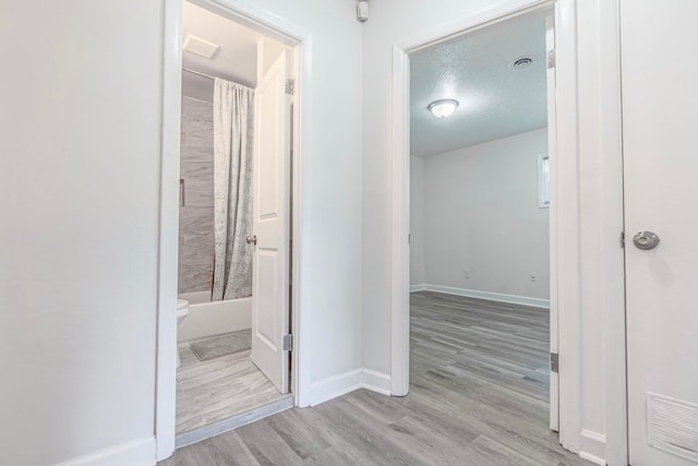 hall featuring a textured ceiling and light wood-type flooring