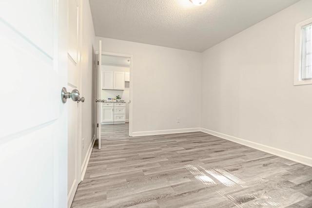 spare room with a textured ceiling and light wood-type flooring