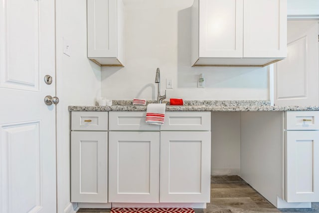 kitchen with hardwood / wood-style flooring, white cabinetry, light stone countertops, and sink