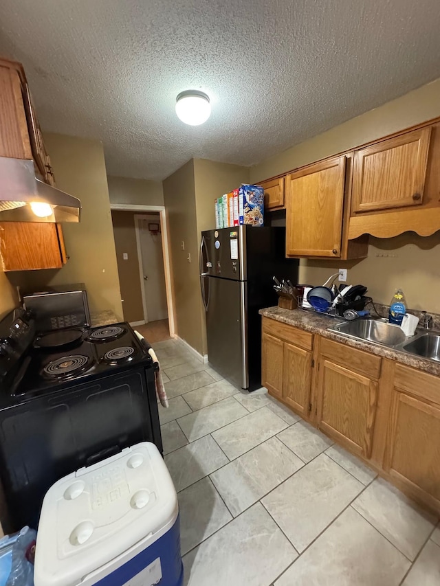 kitchen featuring sink, light tile patterned floors, stainless steel fridge, black electric range, and a textured ceiling