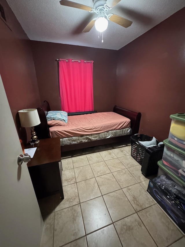 bedroom with ceiling fan, a textured ceiling, and light tile patterned flooring