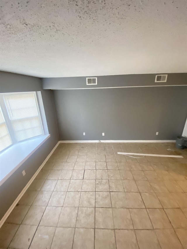 empty room with light tile patterned floors and a textured ceiling