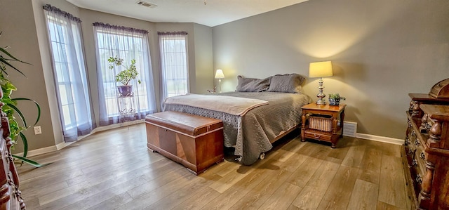 bedroom with multiple windows and light hardwood / wood-style flooring