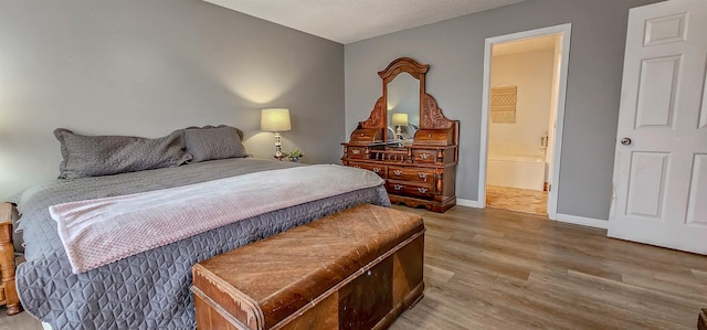 bedroom with wood-type flooring and connected bathroom