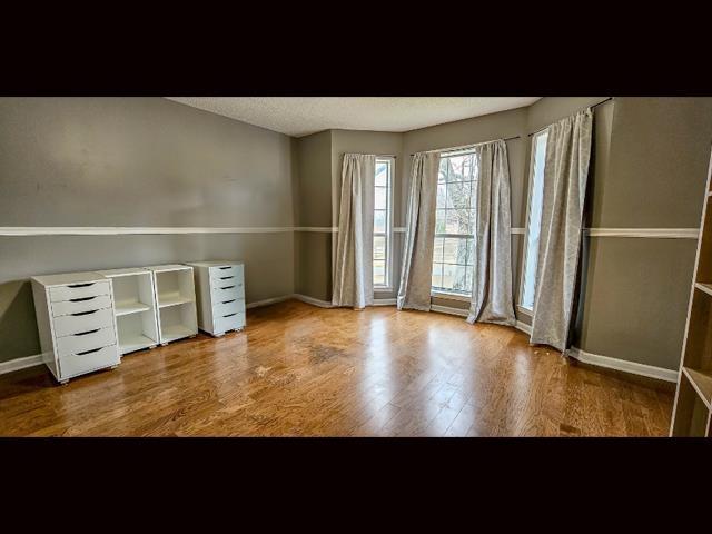 unfurnished room with hardwood / wood-style flooring and a textured ceiling