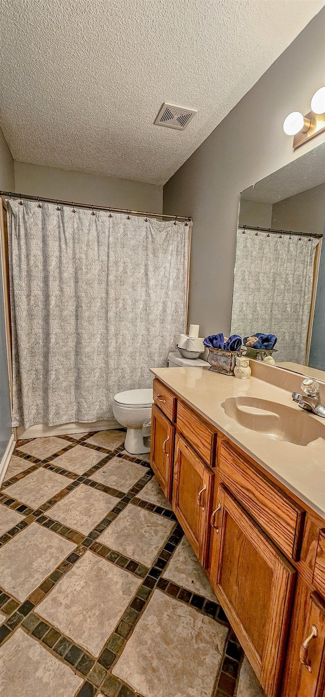 bathroom with vanity, a textured ceiling, and toilet