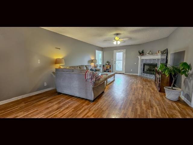 living room with hardwood / wood-style flooring, a tile fireplace, and ceiling fan