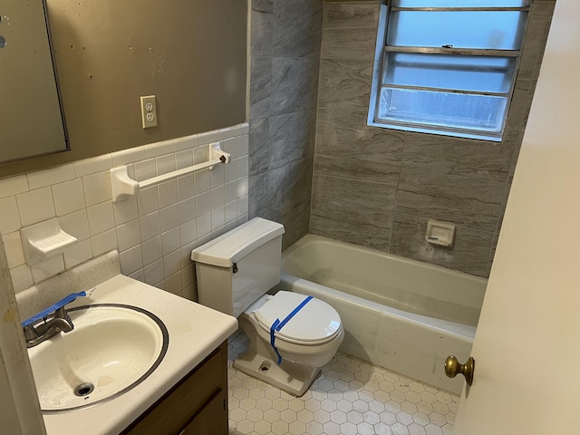 full bathroom featuring tile walls, vanity, tiled shower / bath, and toilet