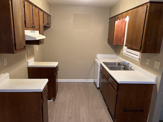 kitchen with white dishwasher, sink, a textured ceiling, and light hardwood / wood-style flooring