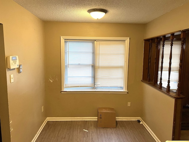 empty room with wood-type flooring and a textured ceiling