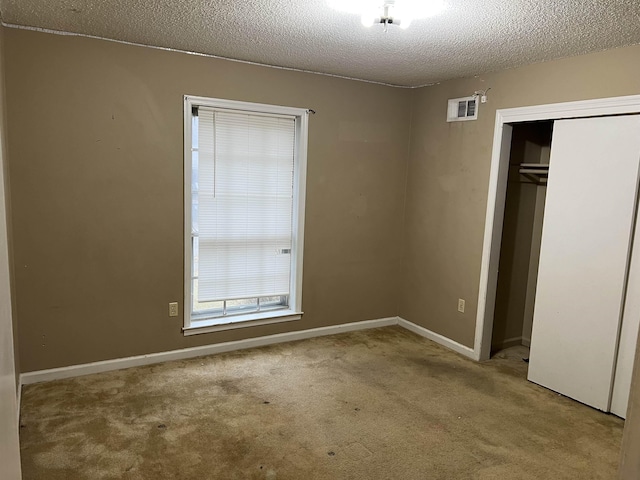 unfurnished bedroom with light carpet, a textured ceiling, and a closet