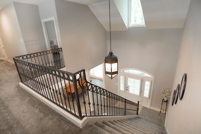 staircase featuring carpet floors and high vaulted ceiling