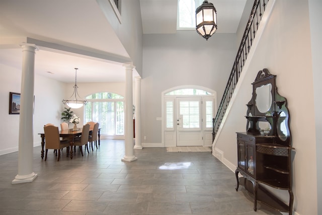 entryway featuring a towering ceiling and decorative columns