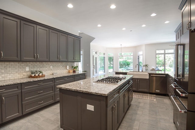 kitchen featuring a kitchen island, decorative light fixtures, tasteful backsplash, sink, and stainless steel appliances