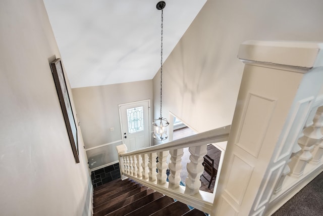 staircase with an inviting chandelier, hardwood / wood-style flooring, and vaulted ceiling