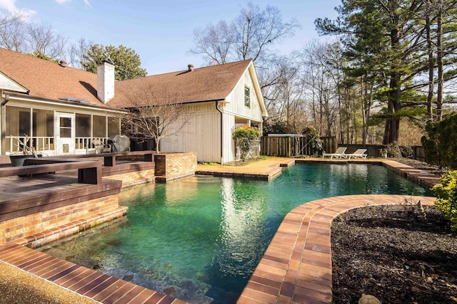 view of swimming pool featuring a wooden deck and a sunroom