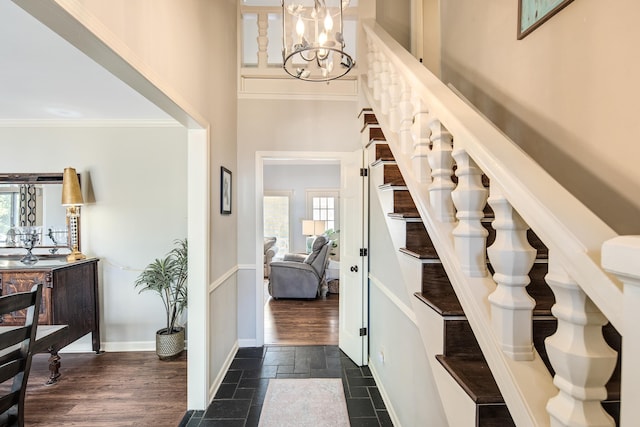 foyer with dark hardwood / wood-style floors, crown molding, a towering ceiling, and a chandelier