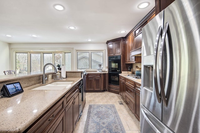 kitchen with light stone countertops, appliances with stainless steel finishes, sink, and dark brown cabinets