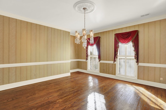 empty room with crown molding, wood-type flooring, and a chandelier