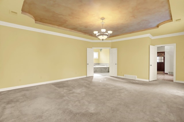 spare room with ornamental molding, carpet floors, an inviting chandelier, and a tray ceiling