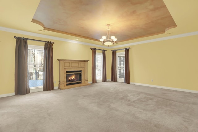 unfurnished living room with a chandelier, ornamental molding, and a raised ceiling