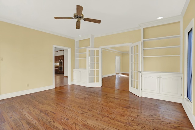 spare room featuring french doors, wood-type flooring, crown molding, and built in features