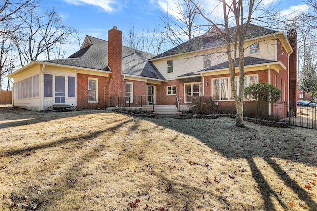 back of property with a lawn and a sunroom