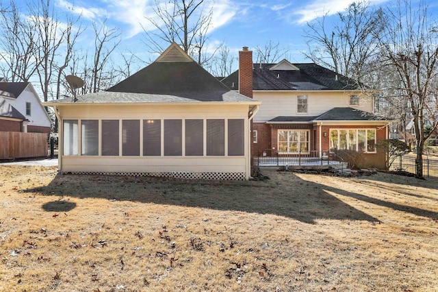 rear view of house featuring a lawn and a sunroom