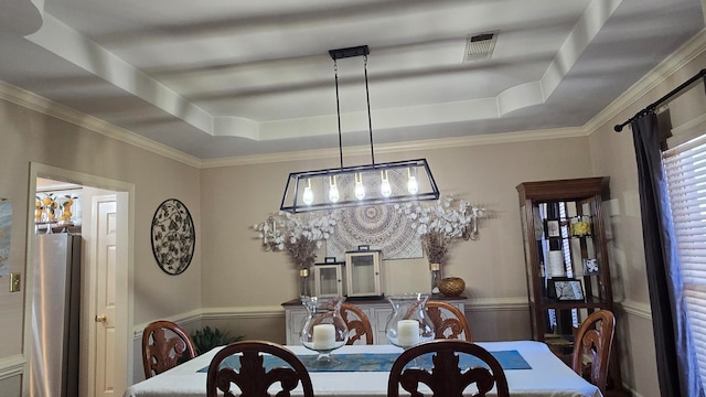 dining room with ornamental molding and a tray ceiling