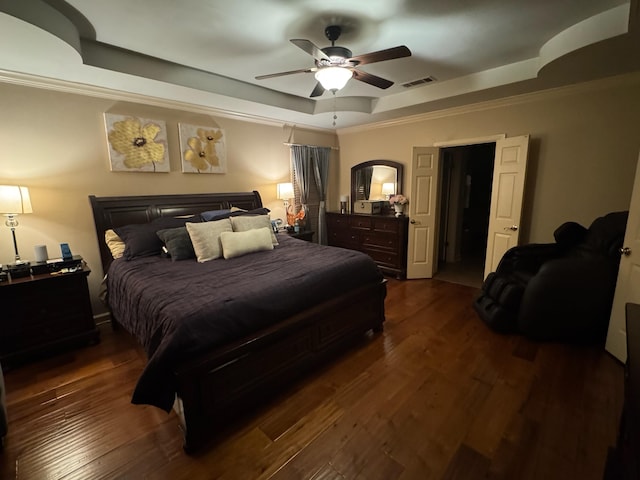 bedroom with ornamental molding, dark hardwood / wood-style flooring, and a raised ceiling