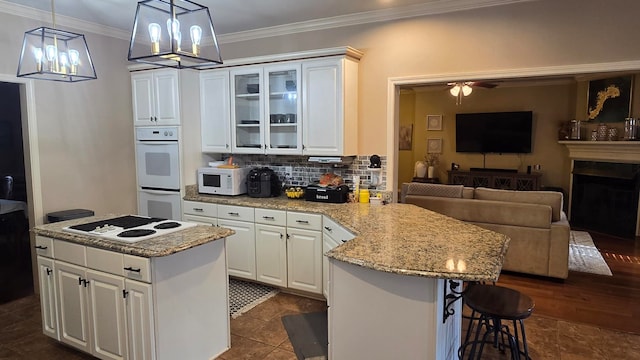 kitchen featuring tasteful backsplash, a kitchen island, pendant lighting, white appliances, and white cabinets