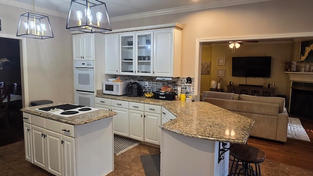 kitchen featuring white cabinetry, white appliances, decorative light fixtures, and a center island