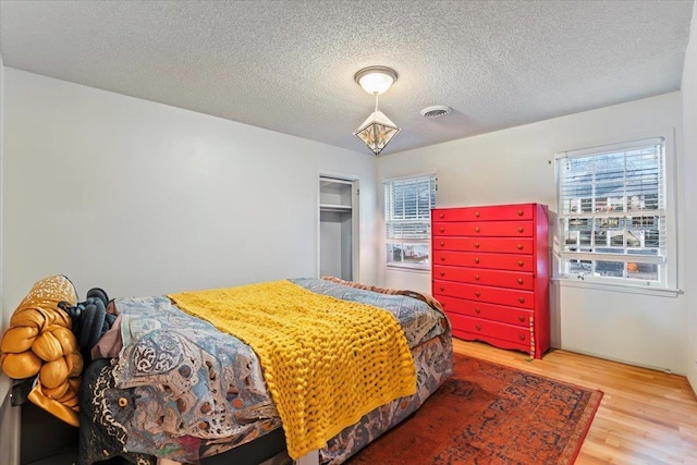 bedroom with multiple windows, wood-type flooring, and a textured ceiling