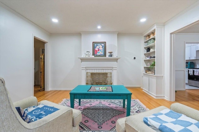 living room featuring hardwood / wood-style flooring, ornamental molding, and a brick fireplace