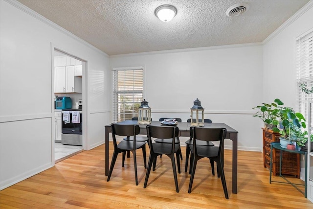 dining space with crown molding, a textured ceiling, and light wood-type flooring