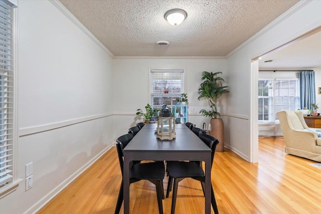 dining area with crown molding, hardwood / wood-style flooring, a textured ceiling, and a healthy amount of sunlight