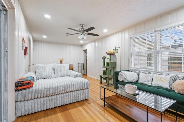 living room with hardwood / wood-style floors, a textured ceiling, and ceiling fan