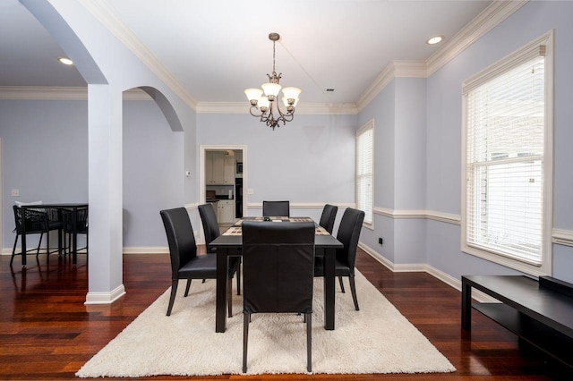 dining area featuring dark wood-type flooring, crown molding, and a notable chandelier