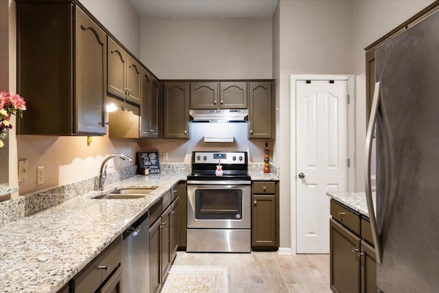 kitchen featuring light stone counters, sink, light wood-type flooring, and appliances with stainless steel finishes