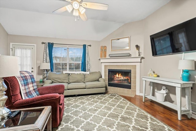 living room with ceiling fan, dark hardwood / wood-style flooring, vaulted ceiling, and a fireplace